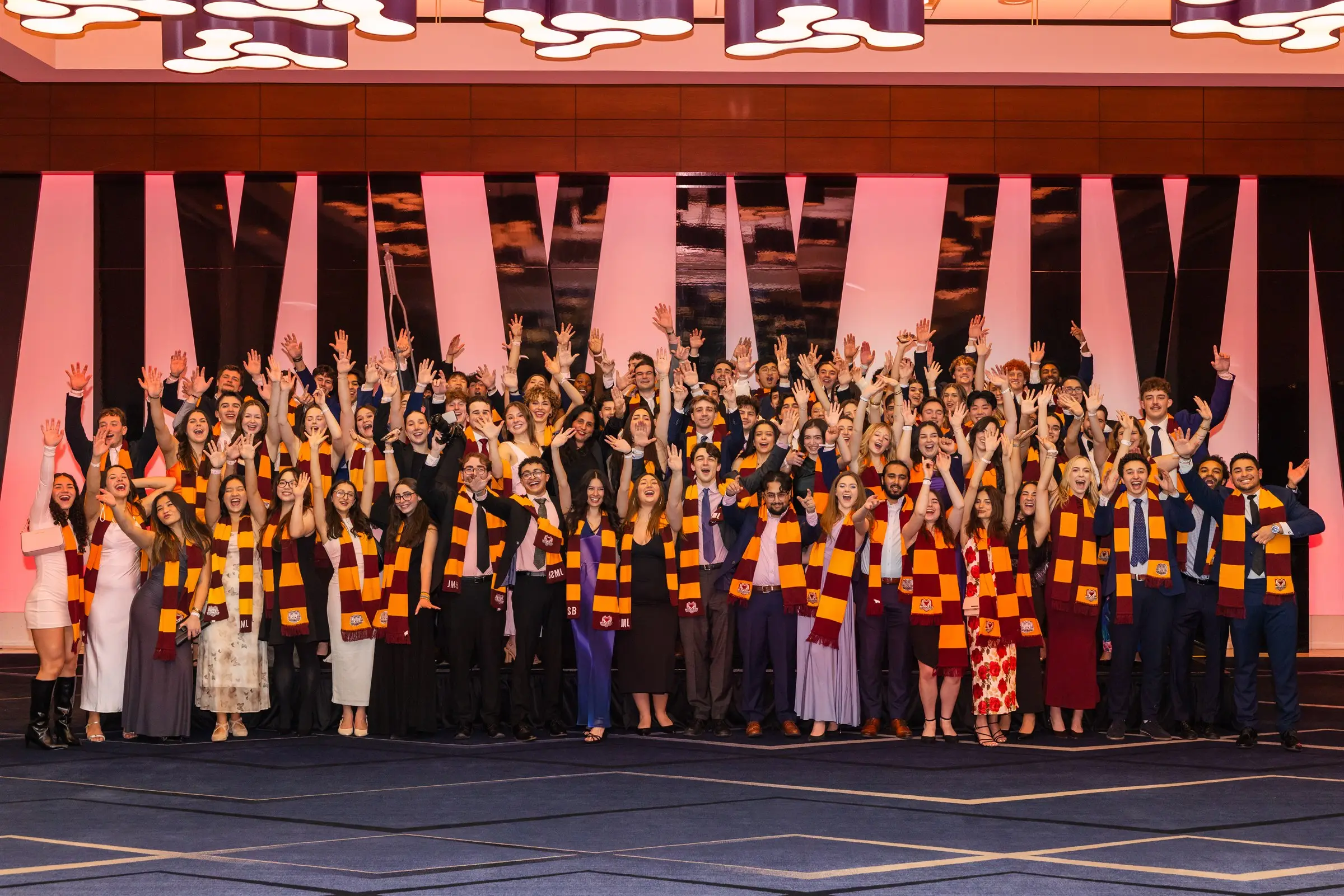 The full JMCC delegation with arms raised, wearing JMCC scarves at the season banquet